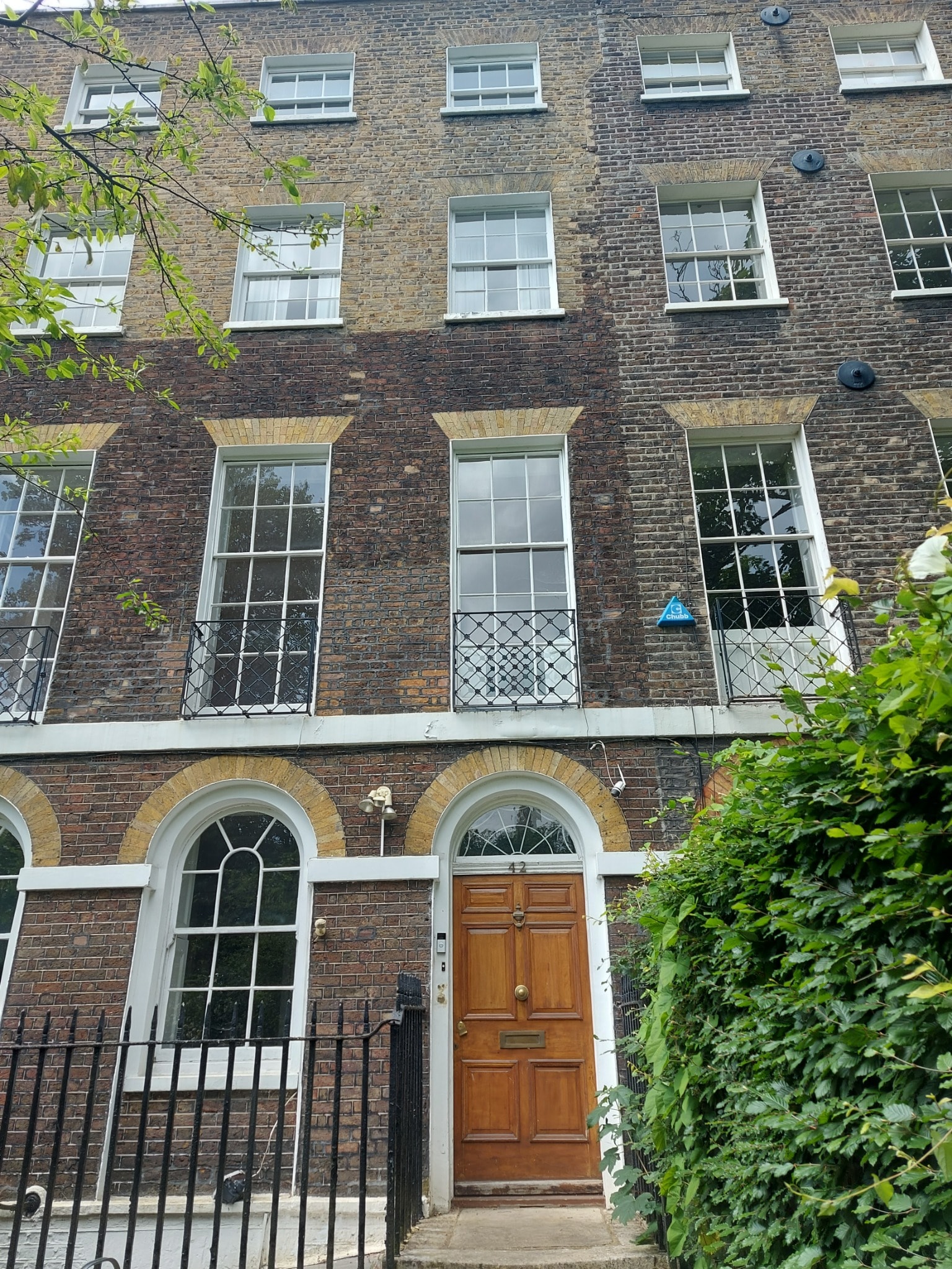 Traditional London townhouse with brick frontage, sash windows, greenery and a wooden front door